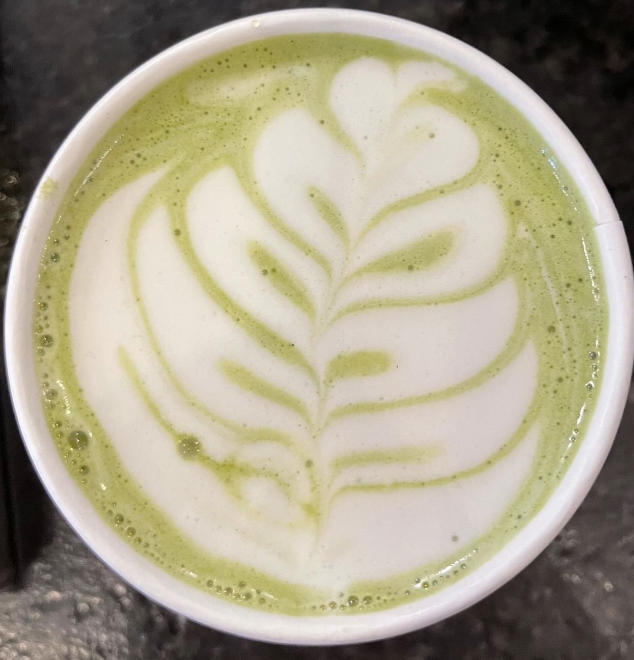 An overhead matcha latte with leaf art